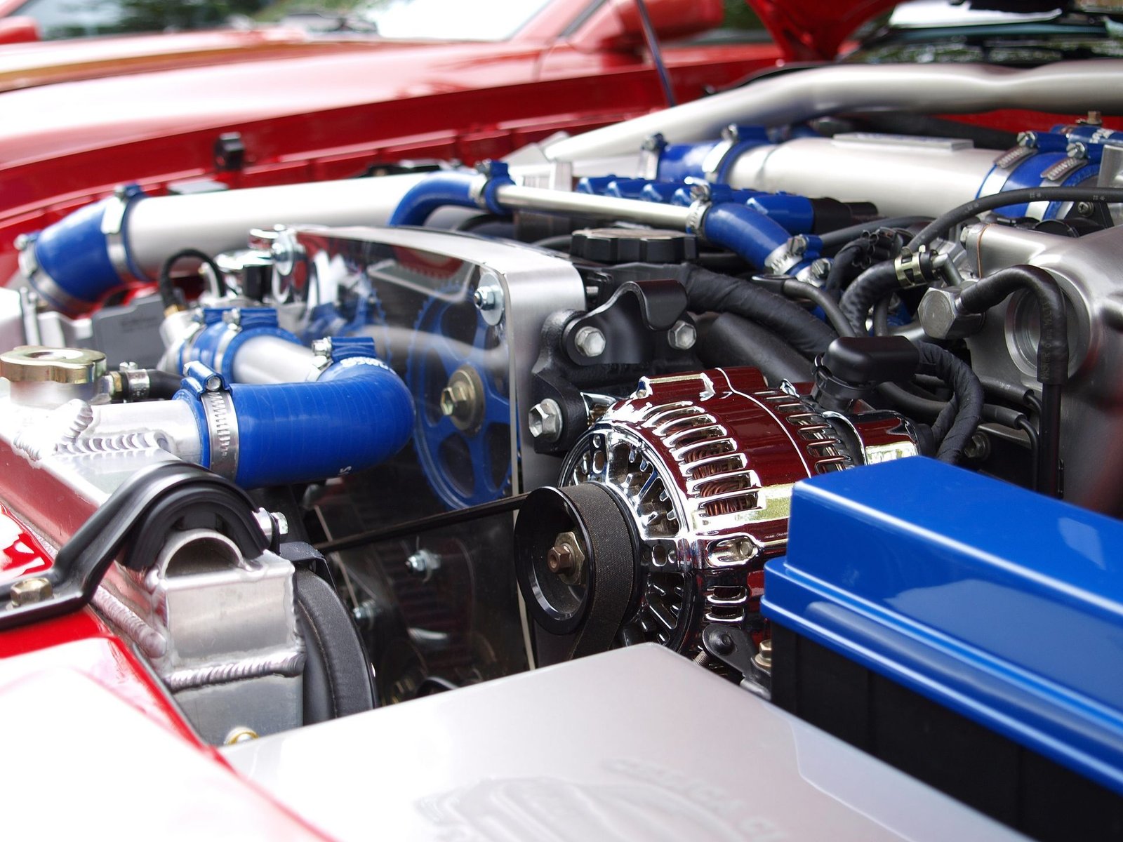 Mechanic using a multimeter to test a car alternator mounted on an engine